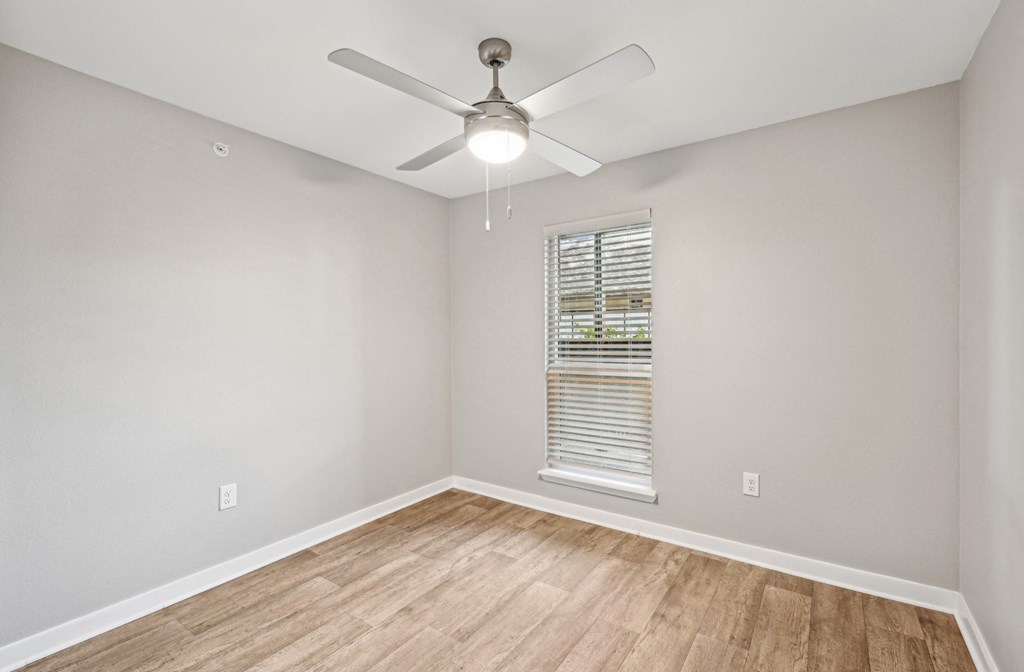 an empty room with a ceiling fan and a window