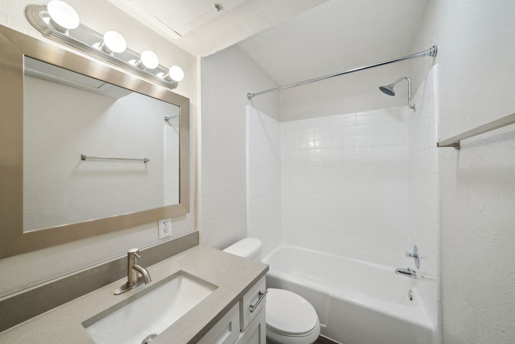 a bright bathroom with a sink toilet and shower and a mirror Woodlands of Plano in Plano, TX