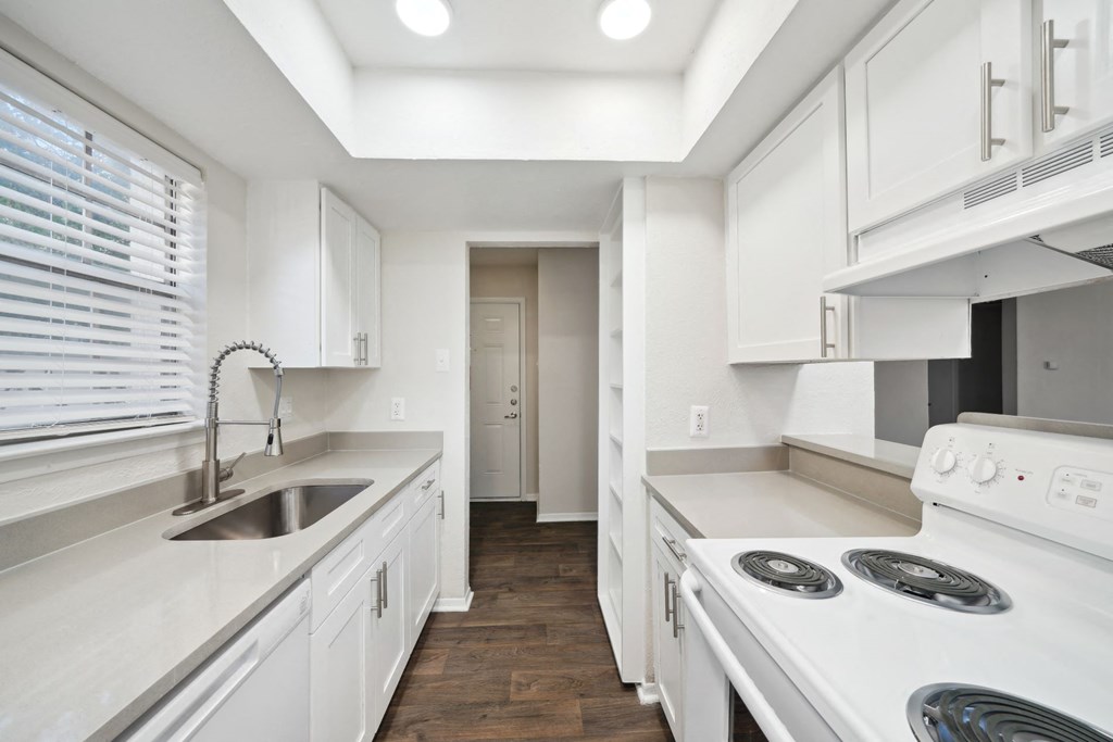 a white kitchen with white appliances and white cabinets at Woodlands of Plano in Plano, TX