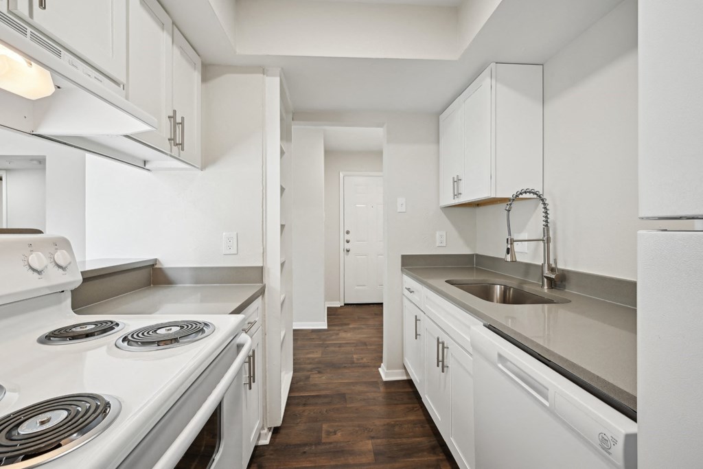 an empty kitchen with white cabinets and appliances and a sink at Woodlands of Plano in Plano, TX