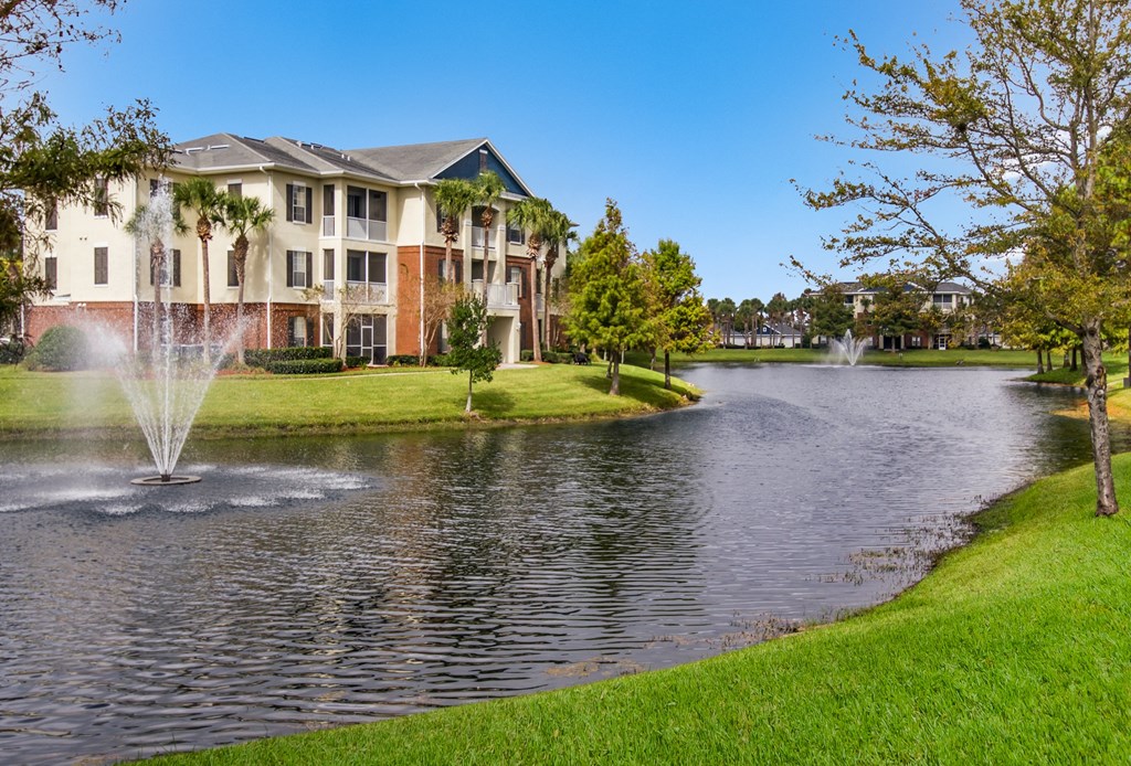 a pond with a fountain in front of an apartment building