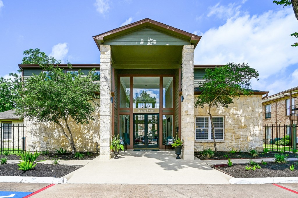 a brick building with a green roof and large glass doors