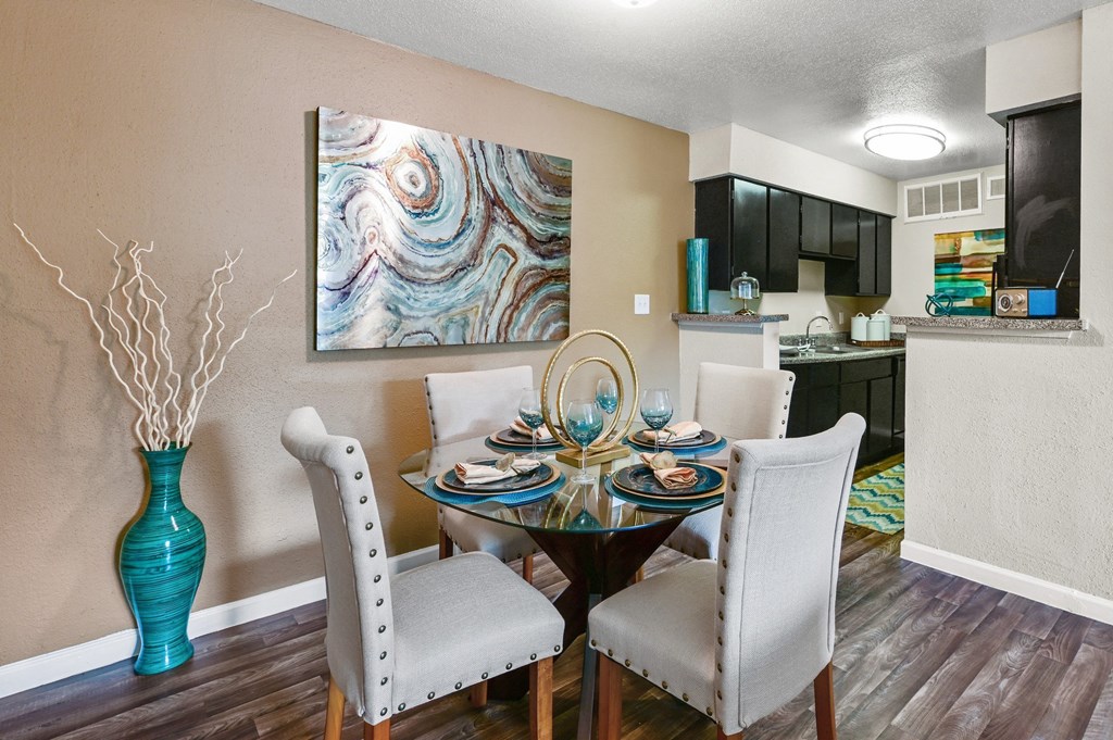 a dining room with a table and chairs and a kitchen in the background