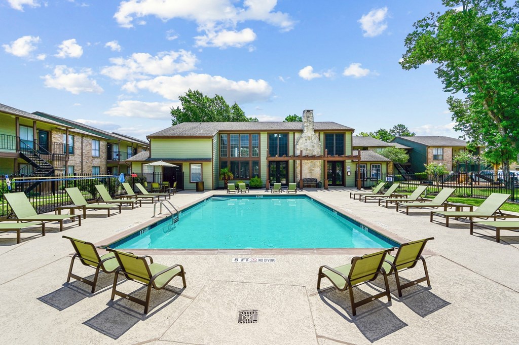 a swimming pool with chaise lounge chairs and a building in the background