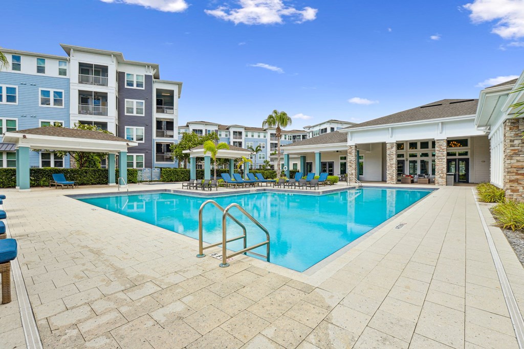 View of our swimming pool with apartment buildings in the background at Dunedin Commons apartments in Dunedin, FL