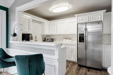 a kitchen with white cabinets and a silver refrigerator