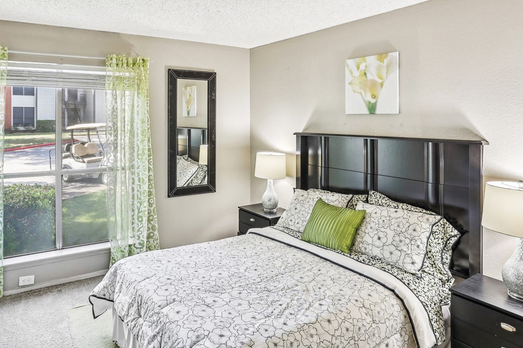 Model apartment bedroom with a bed and a large window at Hunters Chase in Austin, TX