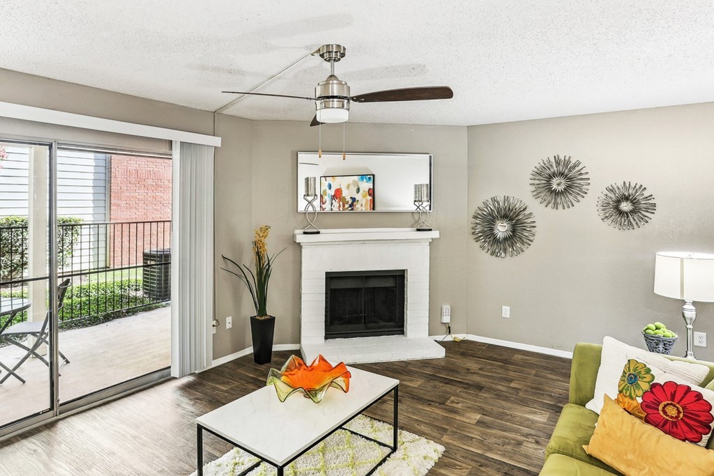 Model living room with a fireplace and a sliding glass door to patio at Hunters Chase in Austin, TX