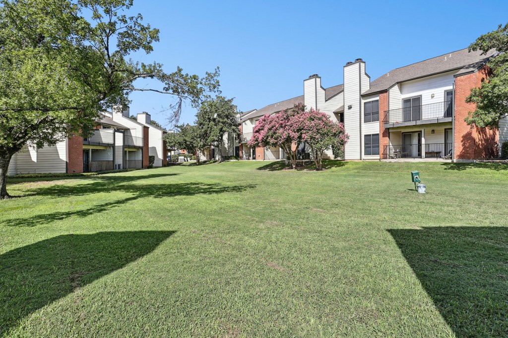 Lush green landscape with pet waste collection stations at Hunters Chase in Austin, TX