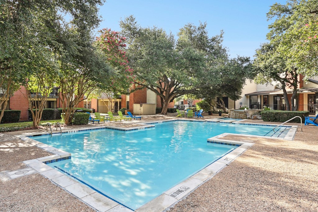 Swimming pool with trees and apartment buildings at Hunters Chase in Austin, TX