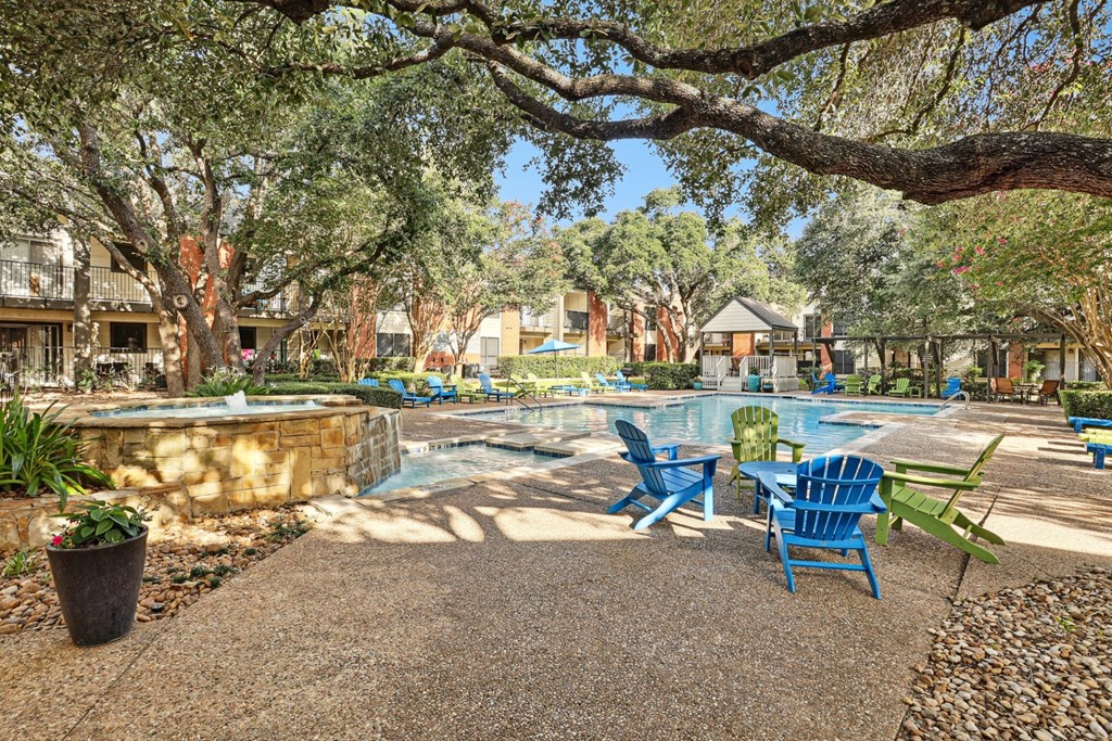 Swimming pool with blue chairs and trees at Hunters Chase in Austin, TX