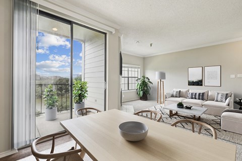 A modern living room  in the A2 floorplan with a wooden table and chairs and a glass sliding door leading to the balcony at Jefferson Creek Apartments in Irving, TX
