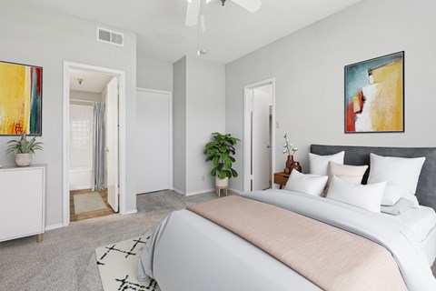 A bedroom in the B1 floorplan with a large bed and a painting on the white wall at Jefferson Creek Apartments in Irving, TX