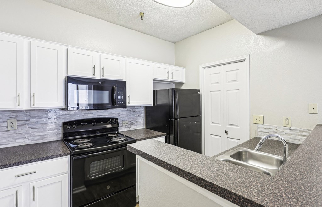 A1 floor plan kitchen with black appliances and elevated counter at Jefferson Creek Apartments in Irving, TX.