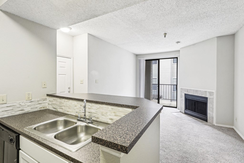 A1 floor plan kitchen with a sink and elevated counter overlooking the fireplace at Jefferson Creek Apartments in Irving, TX.