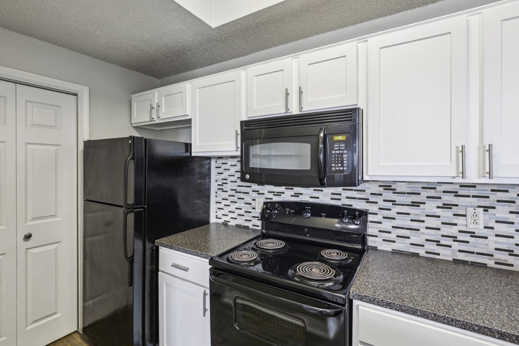 B1 floor plan kitchen with black appliances and white cabinets at Jefferson Creek Apartments in Irving, TX.