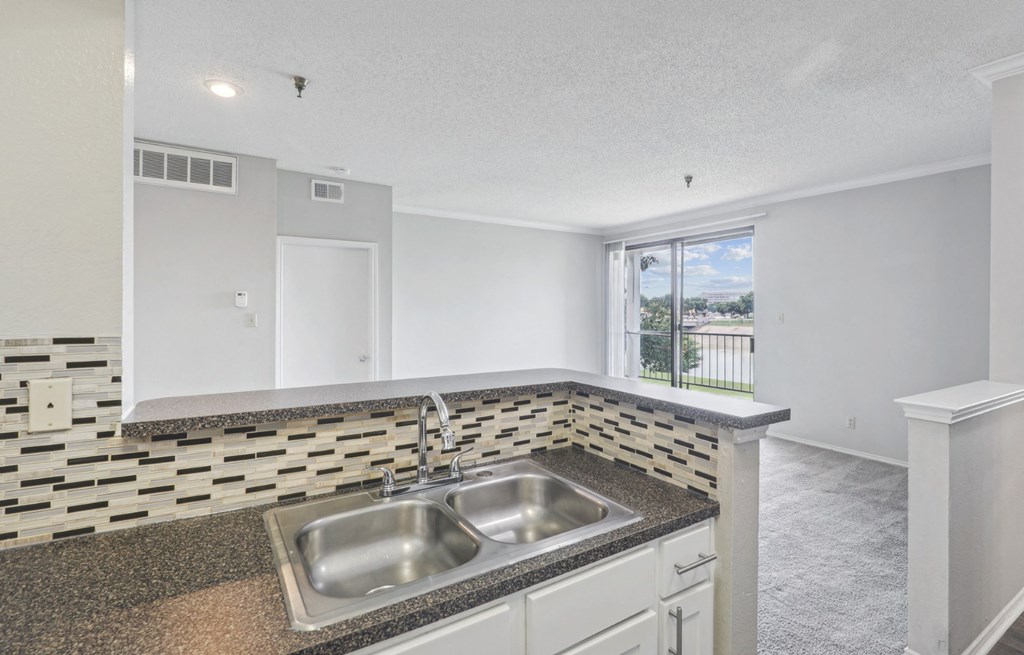 B1 floor plan kitchen sink area with elevated counter overlooking living room at Jefferson Creek Apartments in Irving, TX.