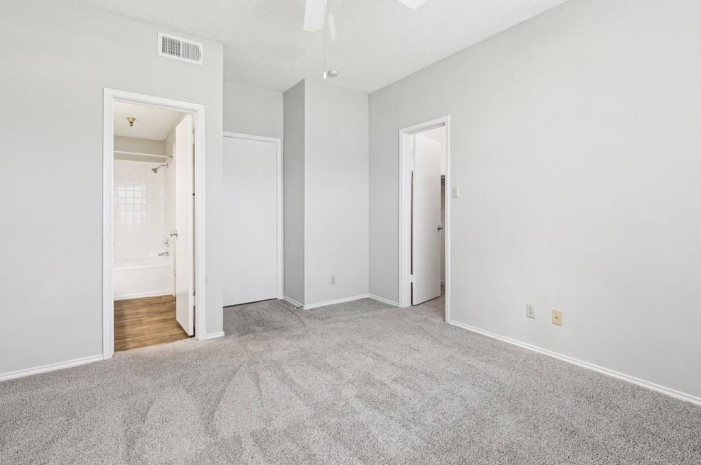 First bedroom at B1 floor plan with walk-in closet and in-room door to bathroom at Jefferson Creek Apartments in Irving, TX.