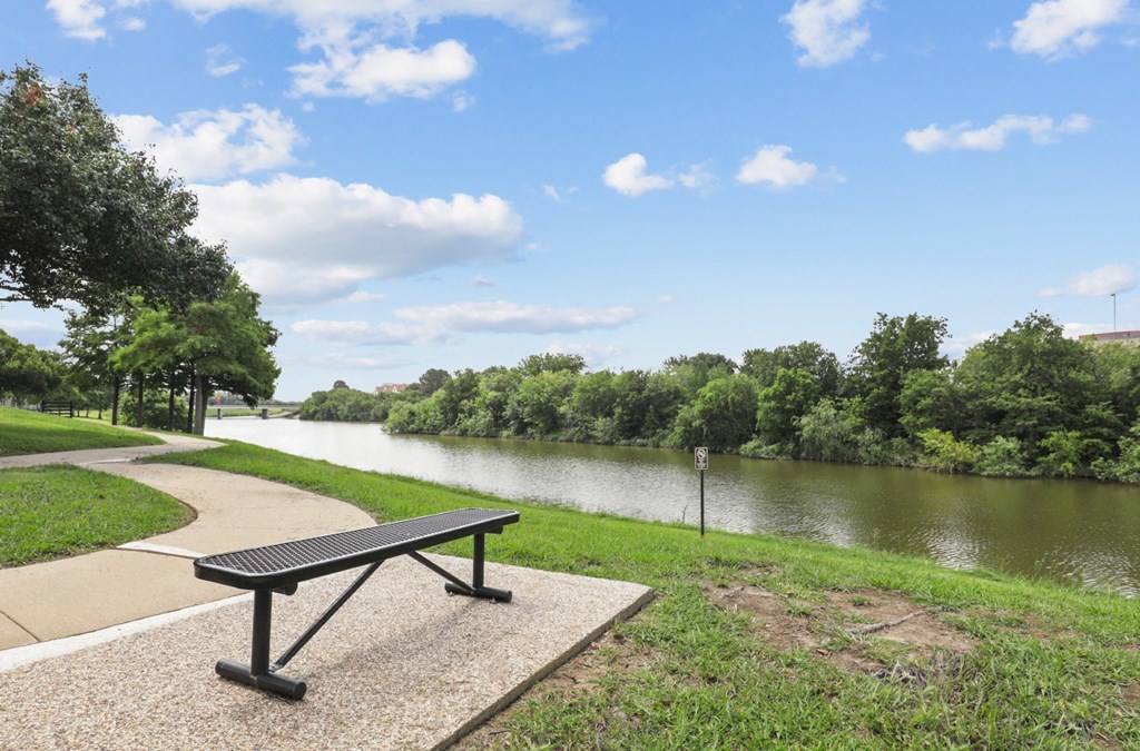 a bench sitting next to a river at Jefferson Creek in Irving, TX