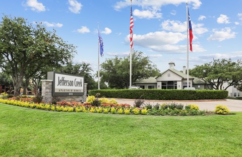 the view of the welcome sign and flags in front of a building