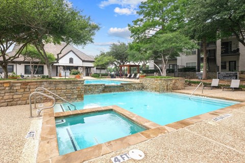 A sparkling pool surrounded by lush trees at Jefferson Place Apartments in Irving, TX