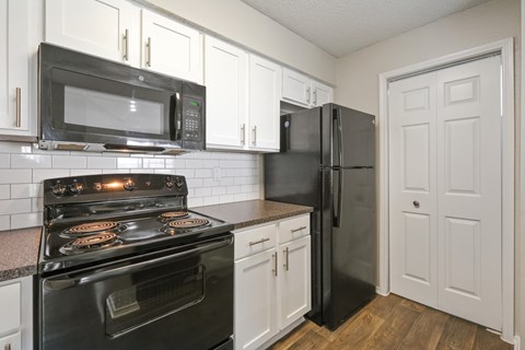 B2 kitchen with black appliances and white cabinets at Jefferson Place Apartments in Irving, TX