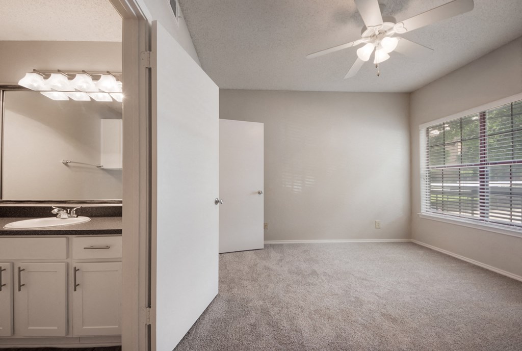 a bedroom with a large window and a ceiling fan