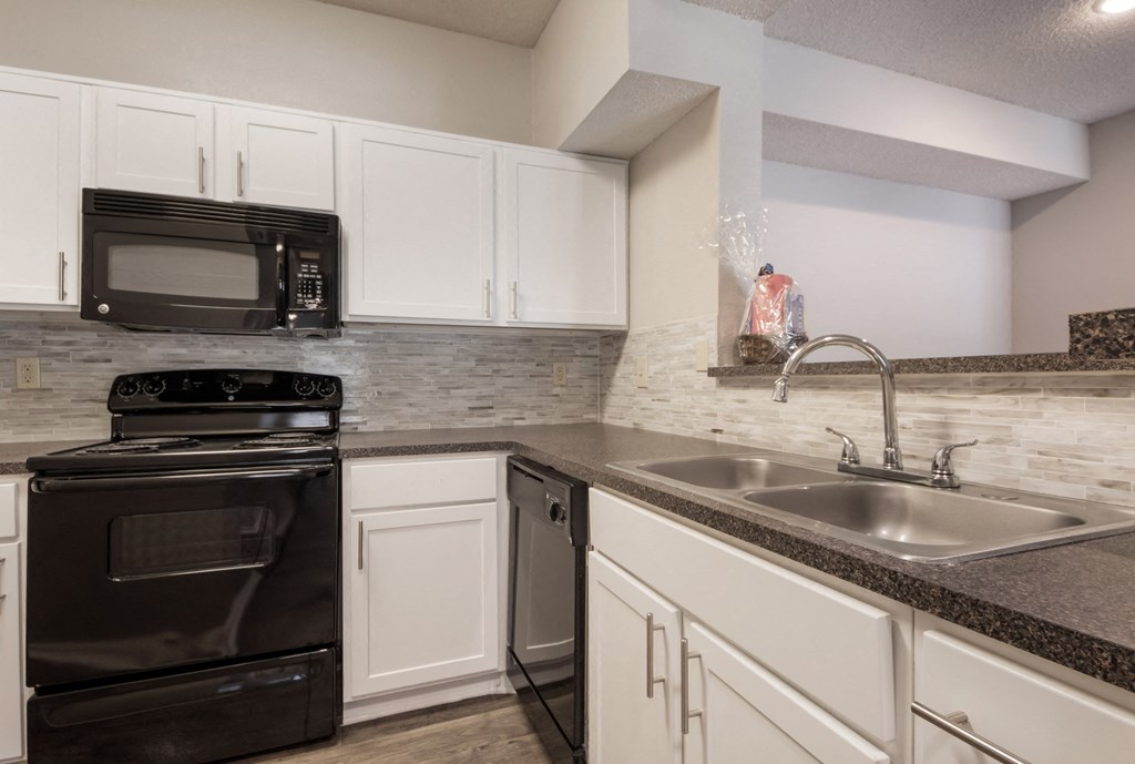 a kitchen with white cabinets and black appliances