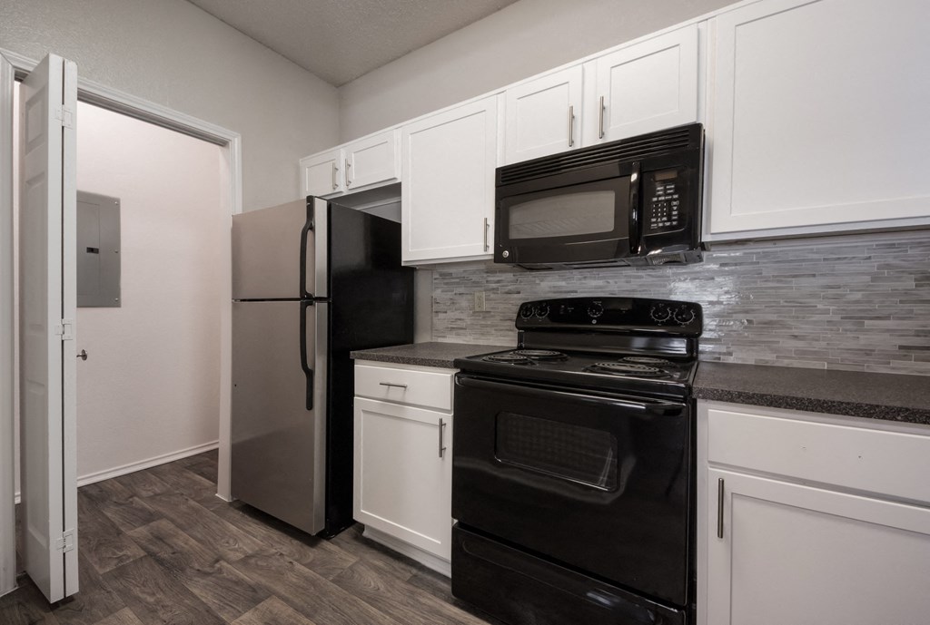 a kitchen with white cabinets and black appliances