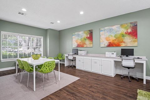 Business center room with computers, printers, and a table with chairs at La Costa Apartments in Plano, TX