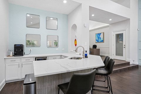 Clubhouse kitchen with a white countertop and black chairs at La Costa Apartments in Plano, TX