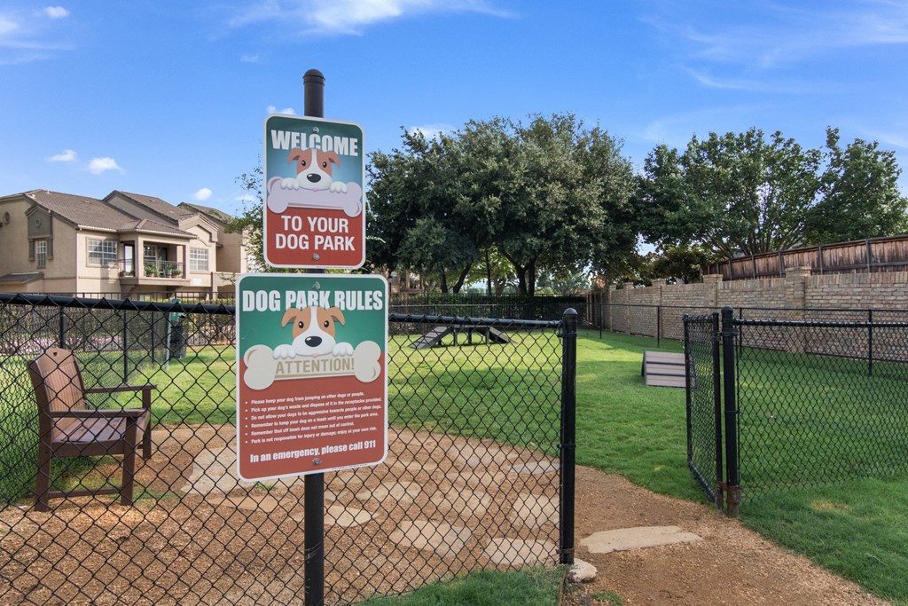 a dog park sign in a fenced in dog park with a fence