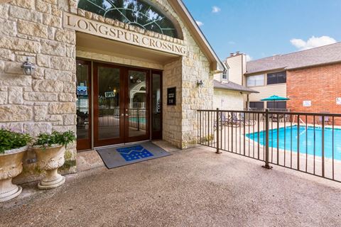 the entrance to longspur crossing apartments with a pool in the background
