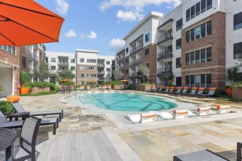 Our beautiful pool surrounded by seating, umbrellas, and more at Muse at Museum District apartments in Houston, TX