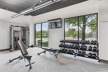 Free weights and workout benches in our state-of-the-art fitness center at Muse at Museum District apartments in Houston, TX