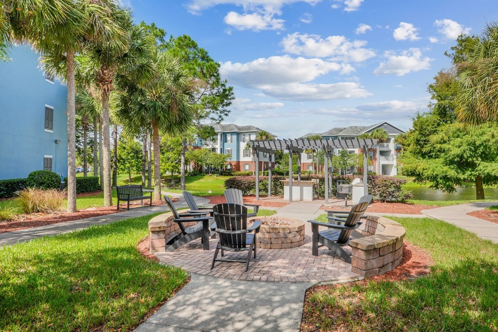 A fire pit with a circular seating area surrounded by lush greenery at Wynnfield Lakes Apartments in Jacksonville, FL