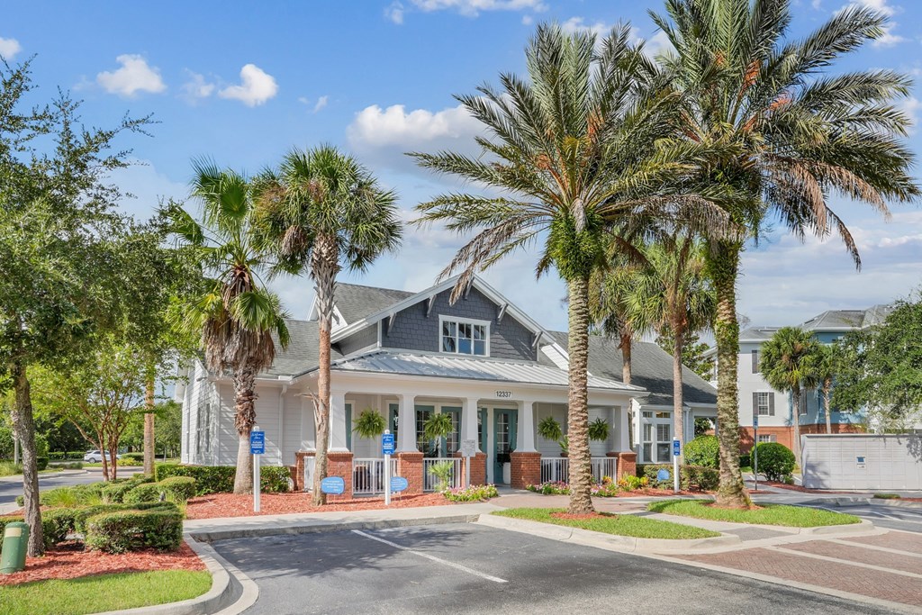 A leasing office with a grey roof is surrounded by palm trees at Wynnfield Lakes Apartments in Jacksonville, FL