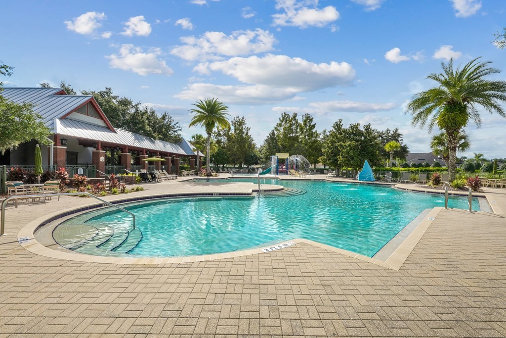 A large outdoor swimming pool surrounded by a brick patio and a covered pavilion at Wynnfield Lakes Apartments in Jacksonville, FL
