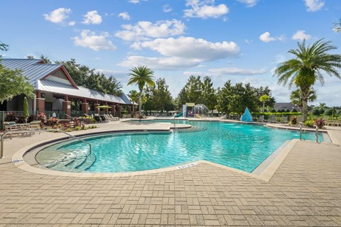 A large outdoor swimming pool surrounded by a brick patio and a covered pavilion at Wynnfield Lakes Apartments in Jacksonville, FL