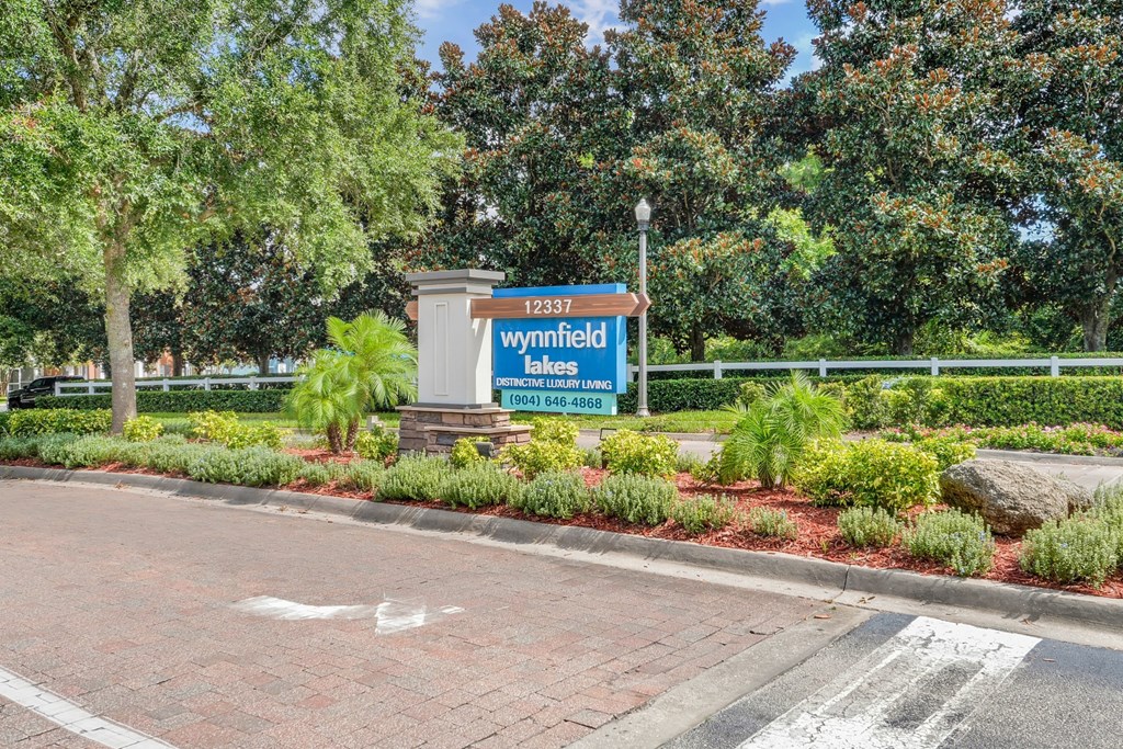 A sign for Wynnfield Lakes is displayed in front of a landscaped area at Wynnfield Lakes Apartments in Jacksonville, FL