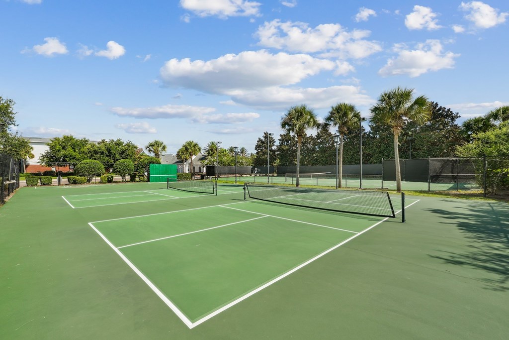 A tennis court surrounded by trees and a fence at Wynnfield Lakes Apartments in Jacksonville, FL