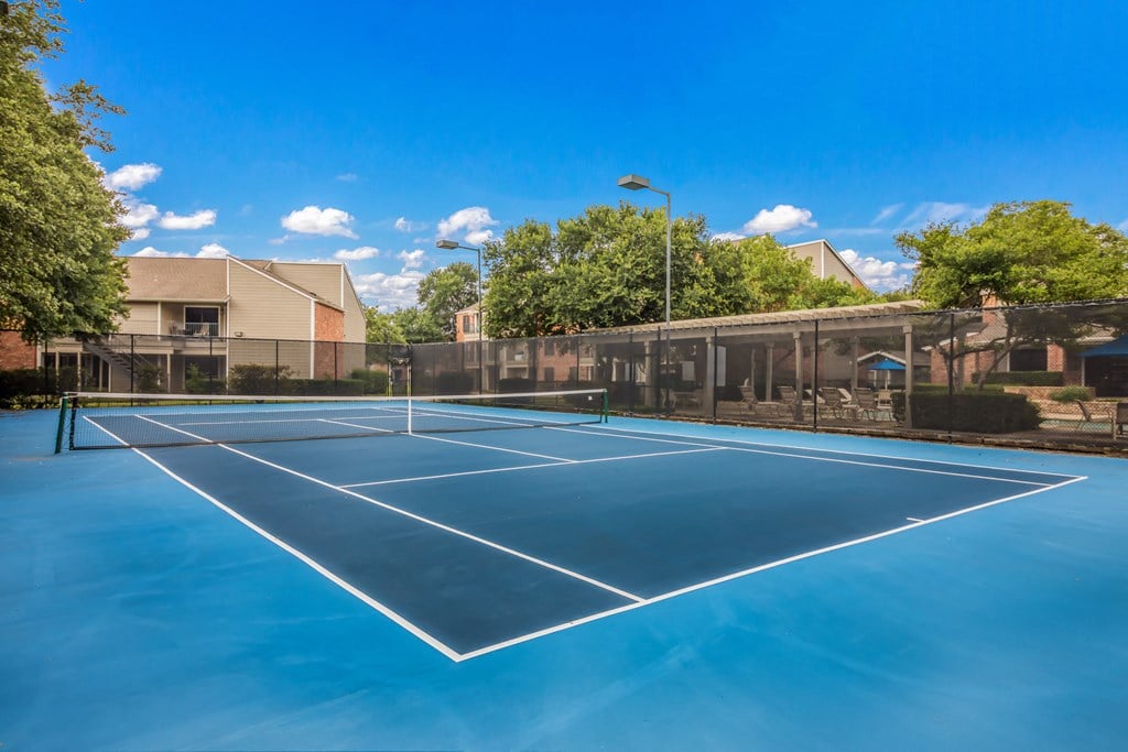a tennis court with apartments in the background