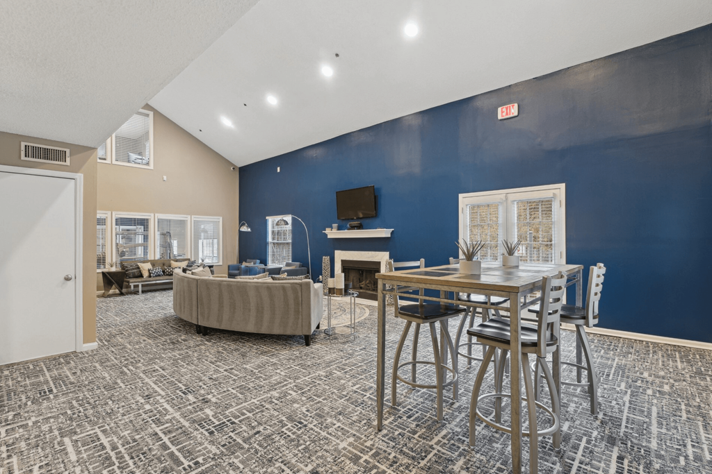 Clubhouse lounge area with couch and a TV above the fireplace at Woodmere Trace apartments in Duluth, GA