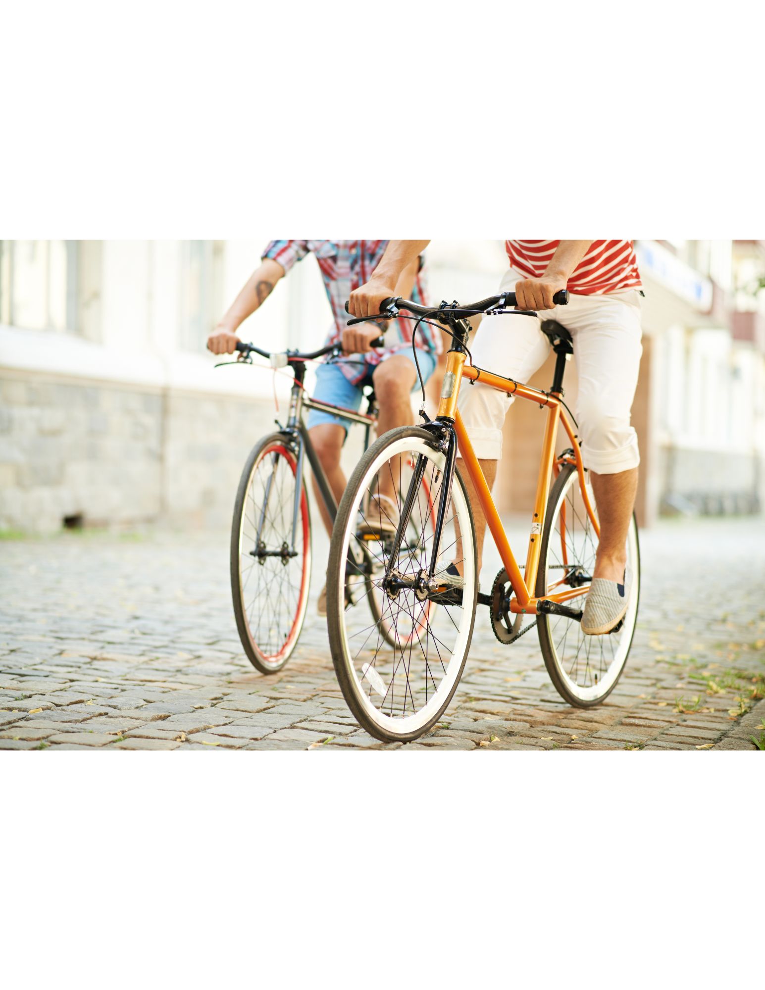 Two people riding bicycles on a cobblestone street.