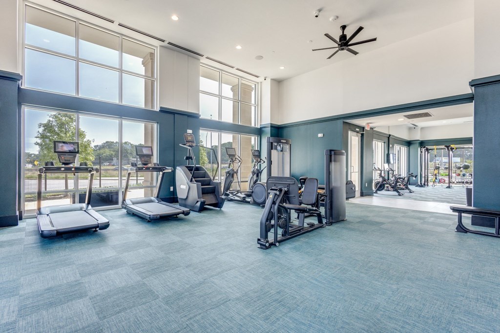 Gym cardio machines and large windows at Era Apartments in Denton, TX
