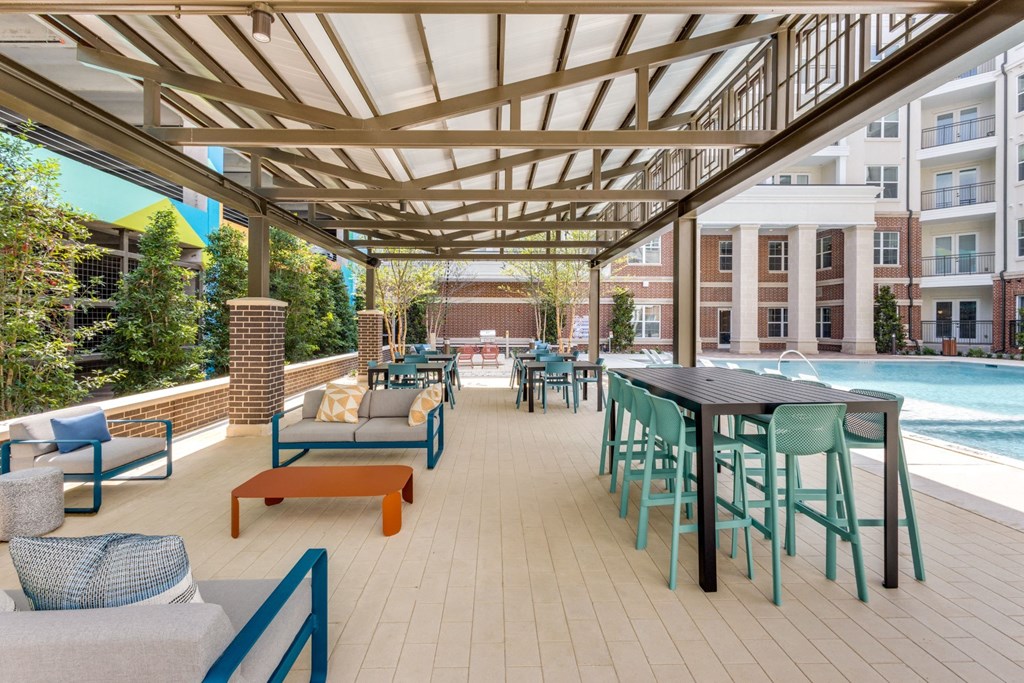 Shaded outdoor patio seating by the pool at Era Apartments in Denton, TX