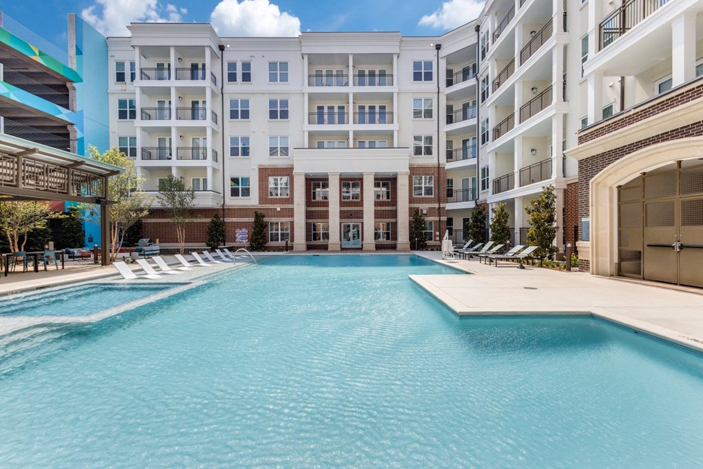 Sparkling swimming pool with Era building in the background at Era Apartments in Denton, TX