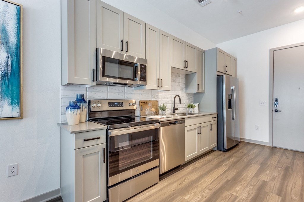 Model Studio kitchen with stainless steel appliances and white cabinetry at Era Apartments in Denton, TX
