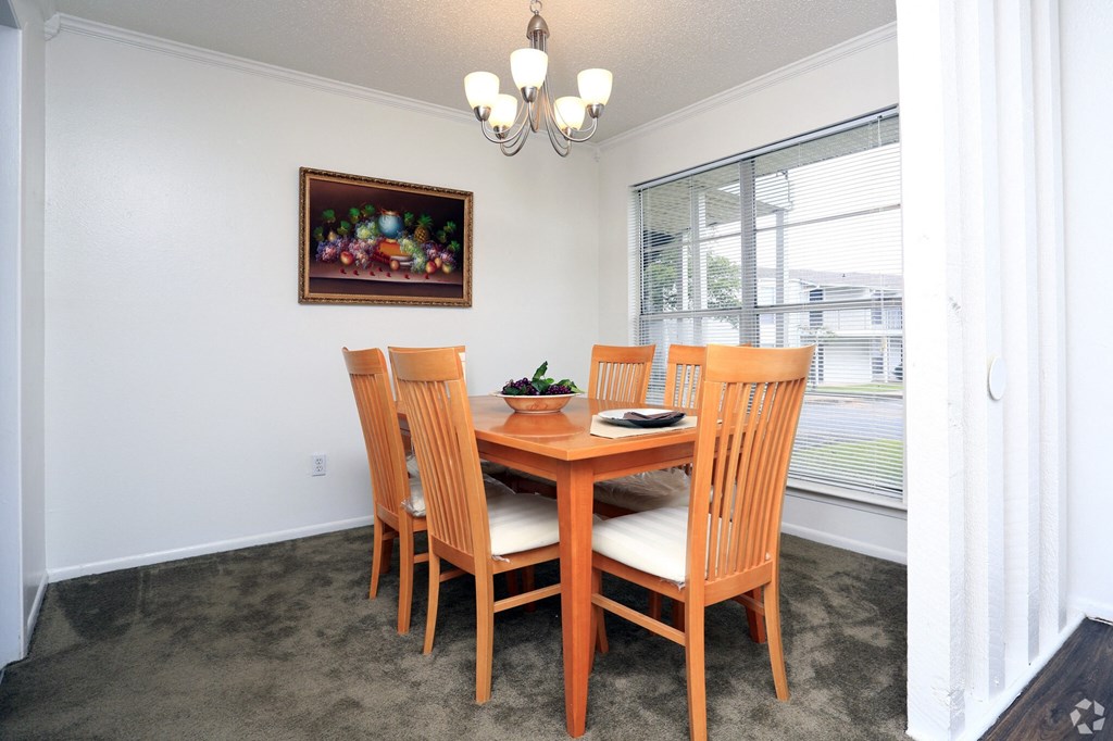 a dining room with a wooden table and chairs and a large window