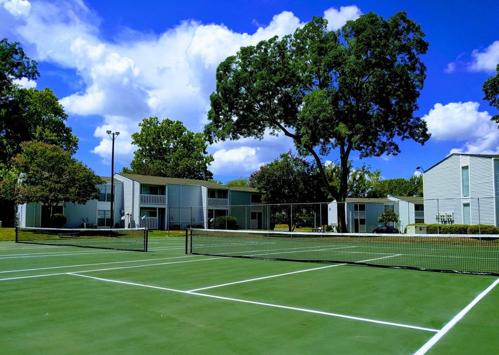 a tennis court with apartments in the background